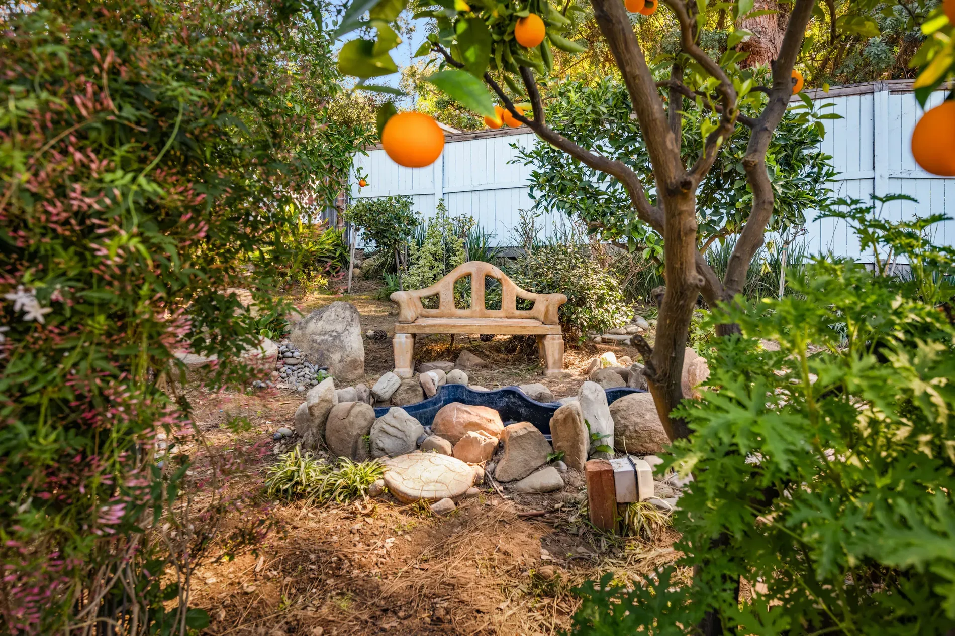 Stone bench tucked in greenery, and yep, orange trees. I’d sit here.