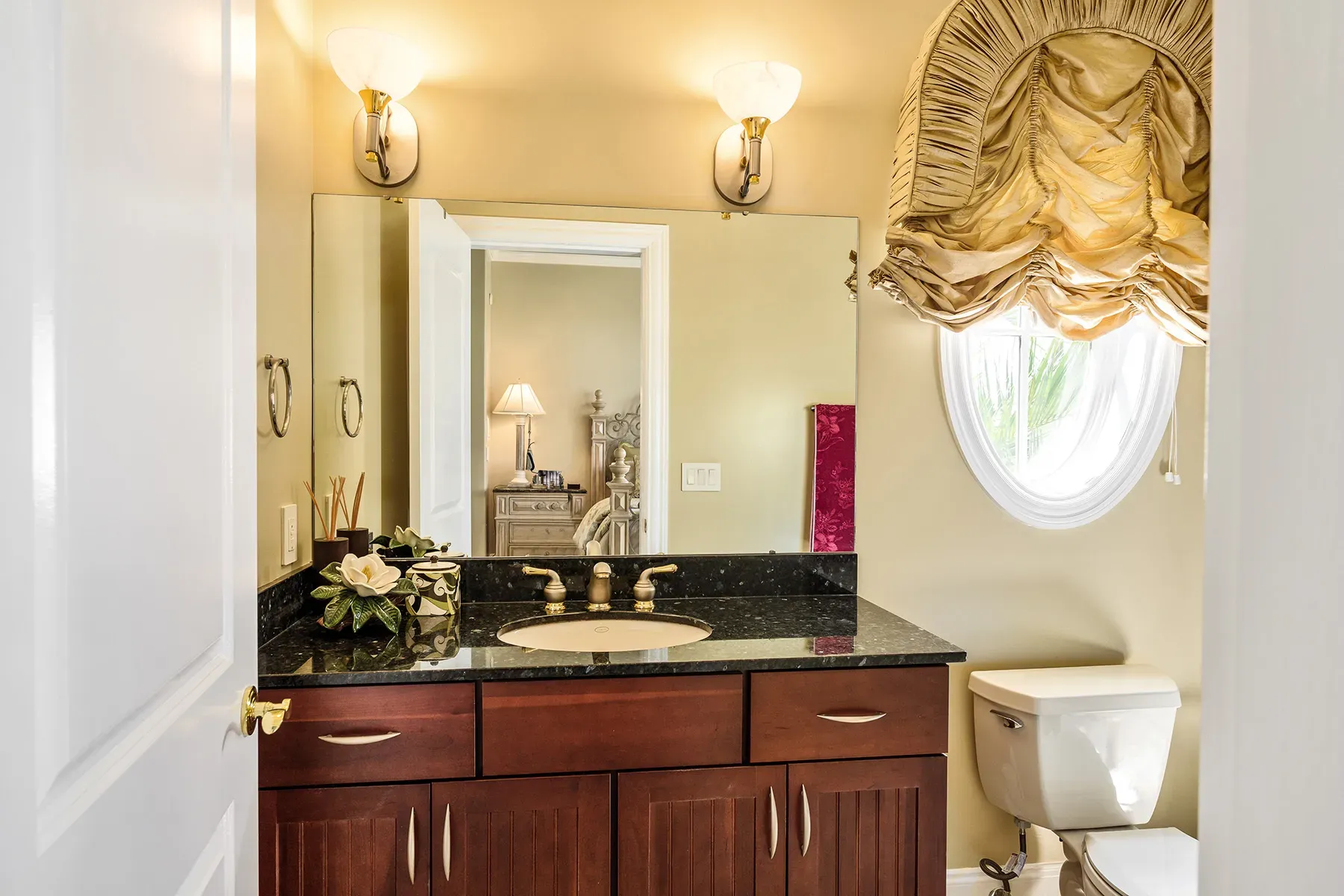 Bathroom leans warm. yellow walls, dark wood vanity, lots of shine.