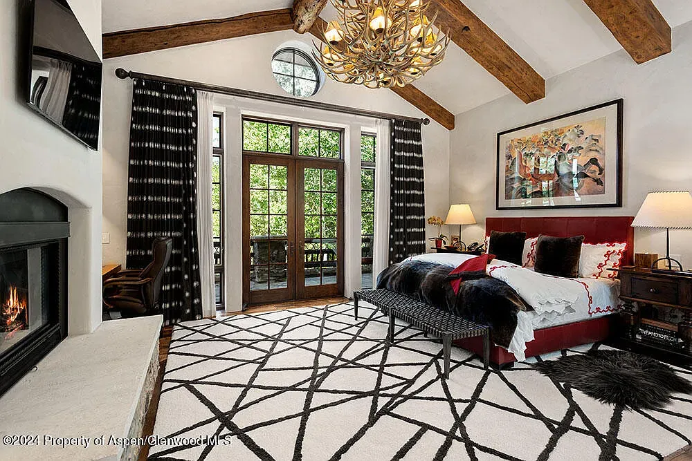 Modern chandelier under big beams. Nice mix in this bedroom.