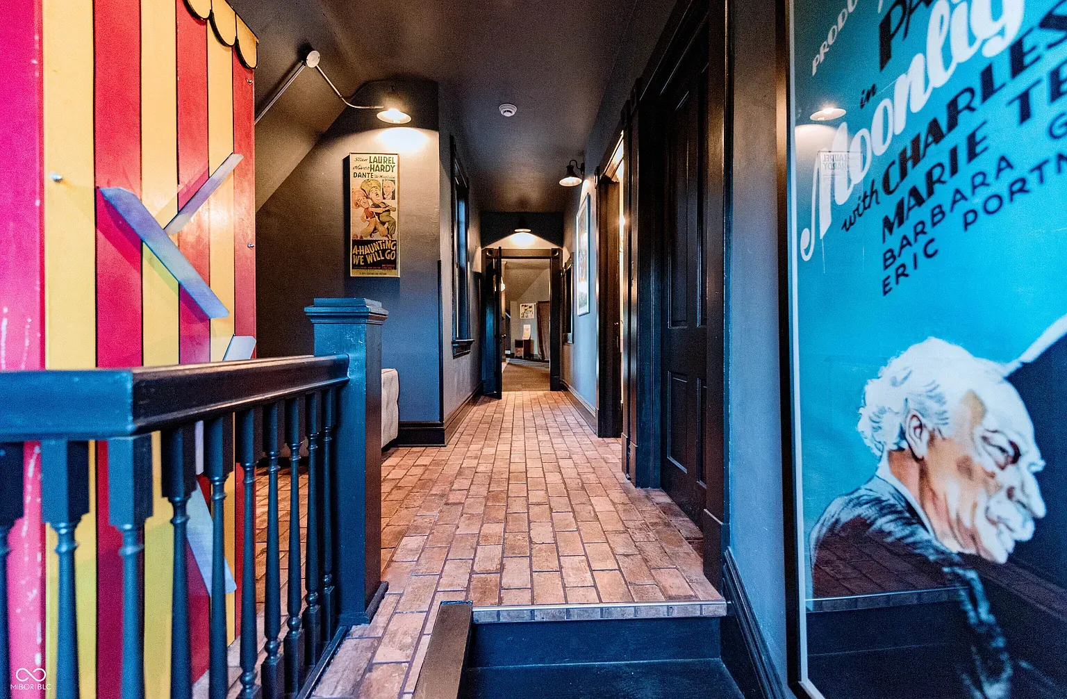 Moody gray hallway lined with posters. Very gallery-meets-secret-tunnel energy.