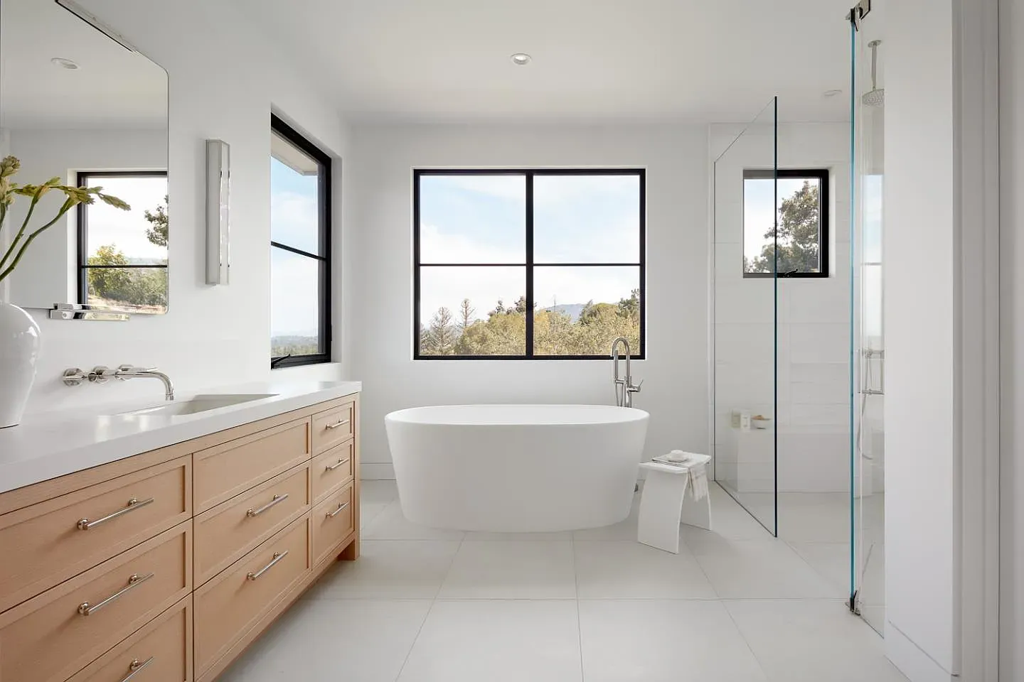 Freestanding tub under black-framed windows. Imagine soaking with that view.