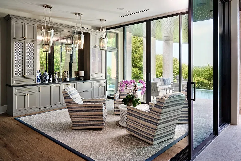 Indoor-outdoor lounge with giant glass walls. Sleek grey cabinetry keeping it tidy.