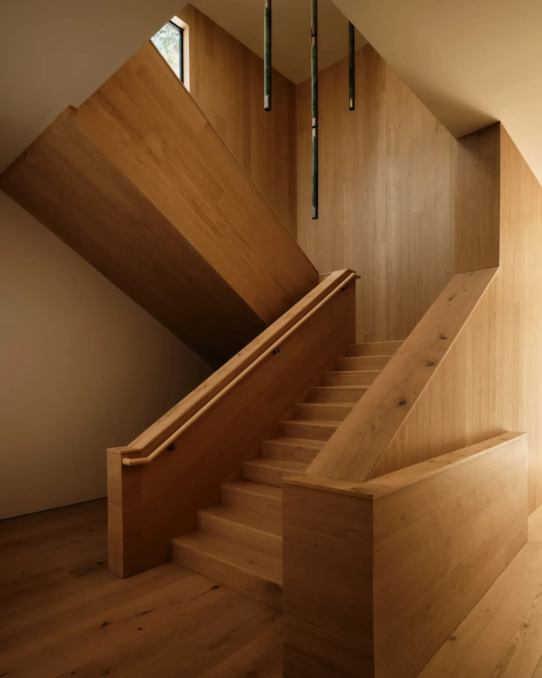 Entry wraps in pale wood. That floating stair is dangerously inviting.