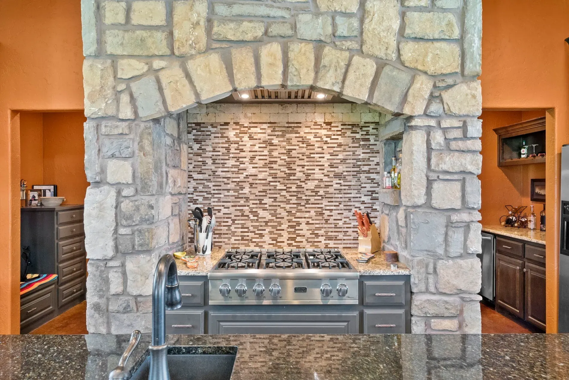 That stone arch over the range is wild. Feels cooking in a lodge.