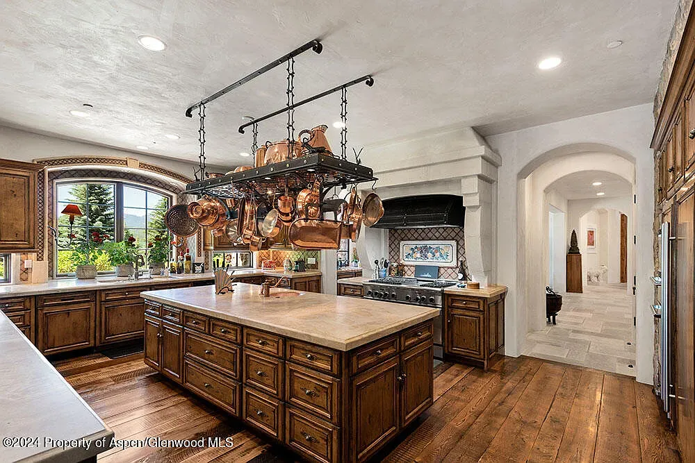 Warm wood kitchen, matte cabinets, big island ready for snacks and chaos.