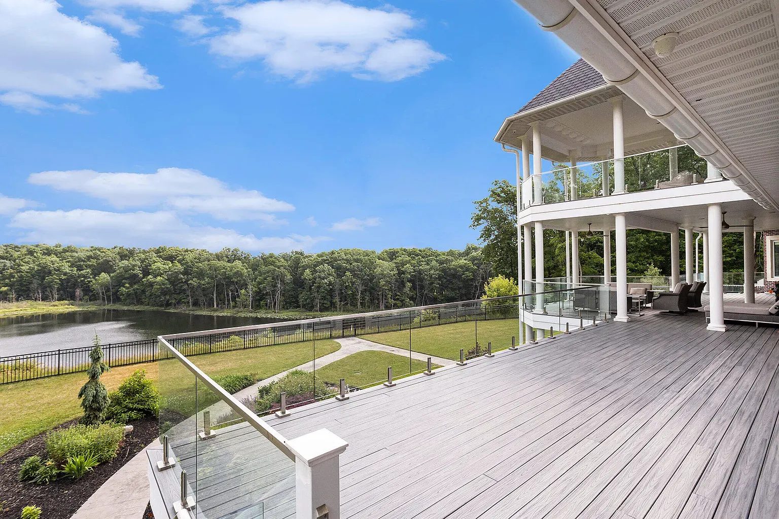 Wraparound deck with glass rails and lake views. I’m moving outside.