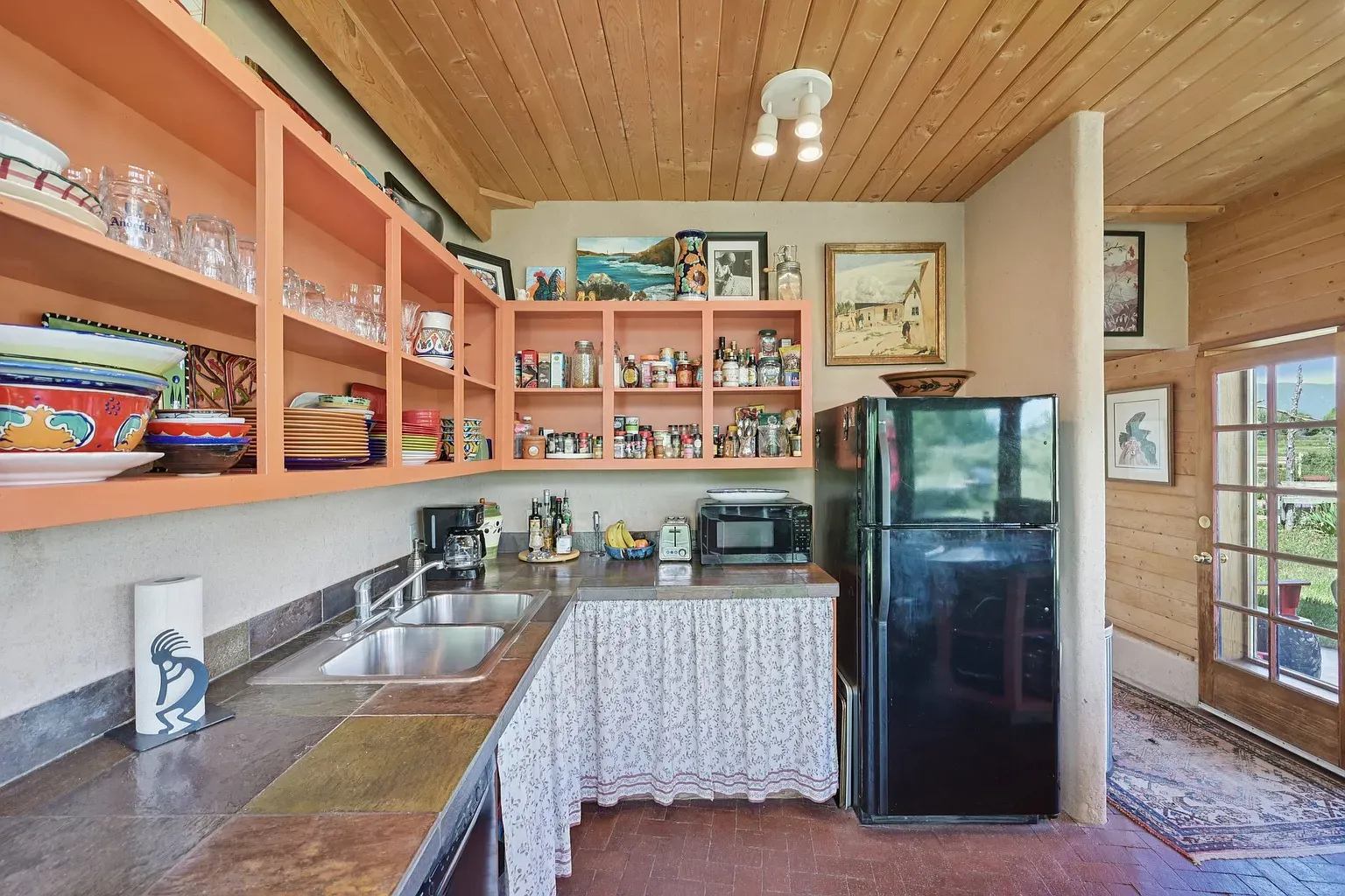 Coral orange shelves stealing the show. Eclectic kitchen vibe but still cookable.
