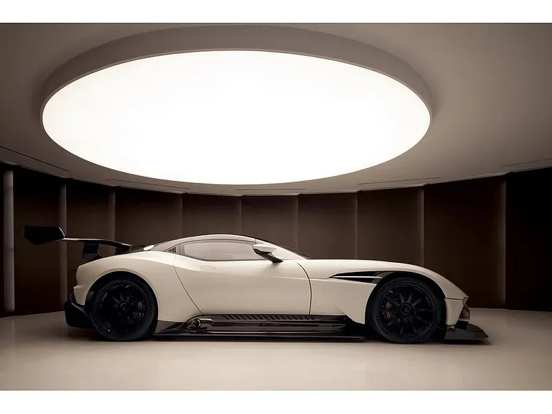 Showroom under a halo skylight. From below, the shadows make the cars feel staged.