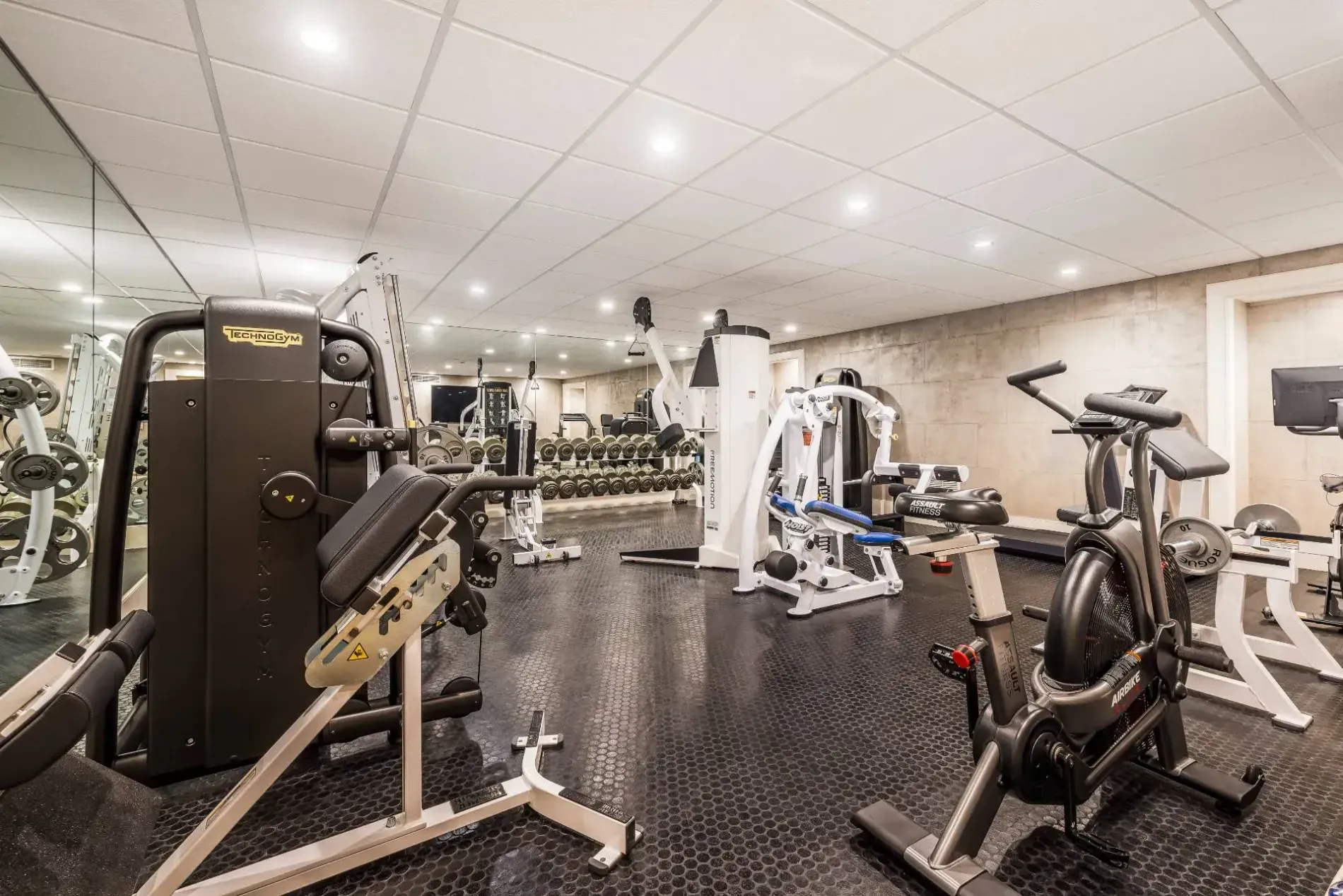 Clean home gym—recessed lights, muted walls. Functional, no clutter. Speakers hidden somewhere?