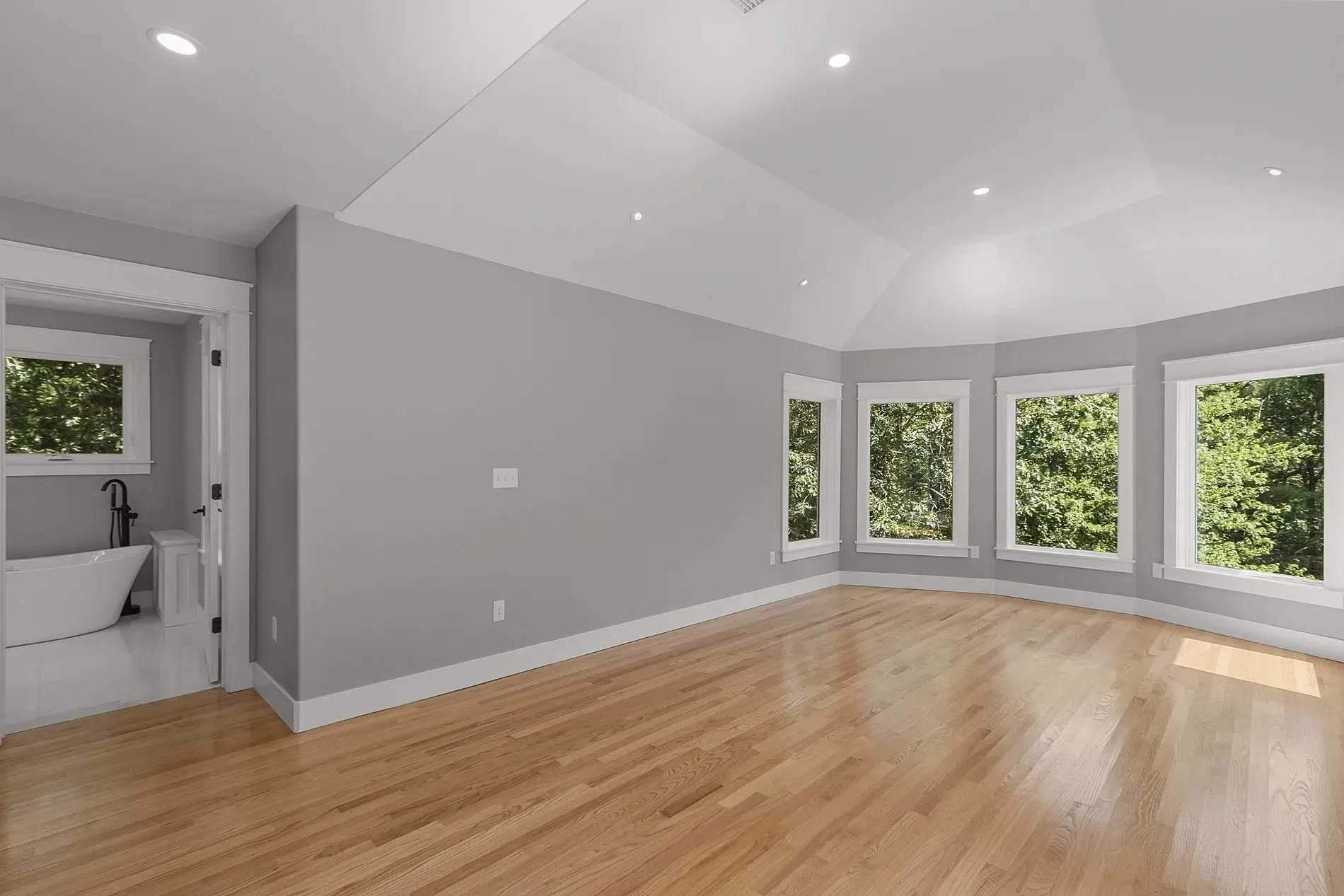 Primary bedroom is calm. muted gray, big windows, and a tray ceiling.