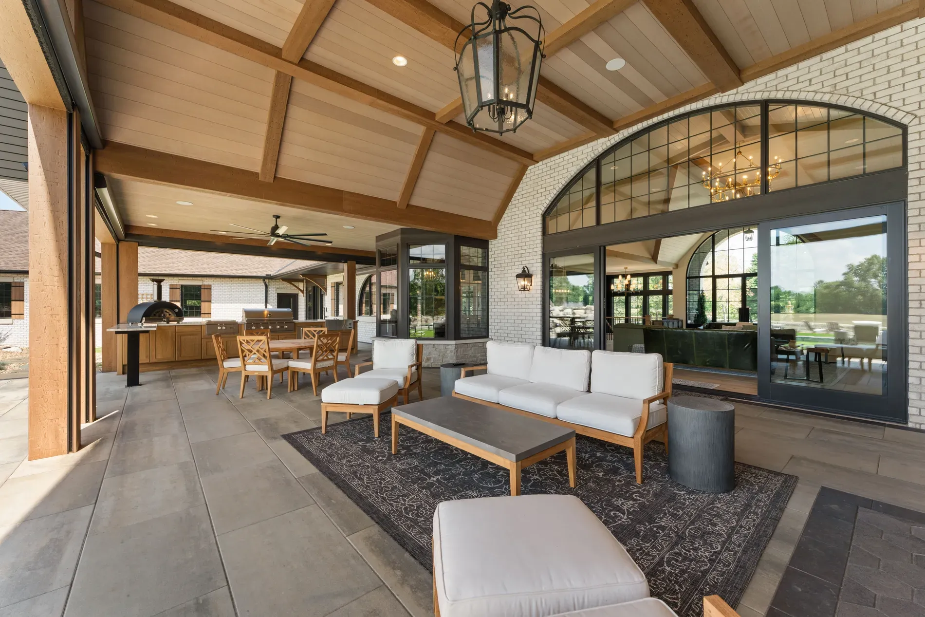 Open patio with huge sloped wood ceiling and black-framed openings. Breezy.