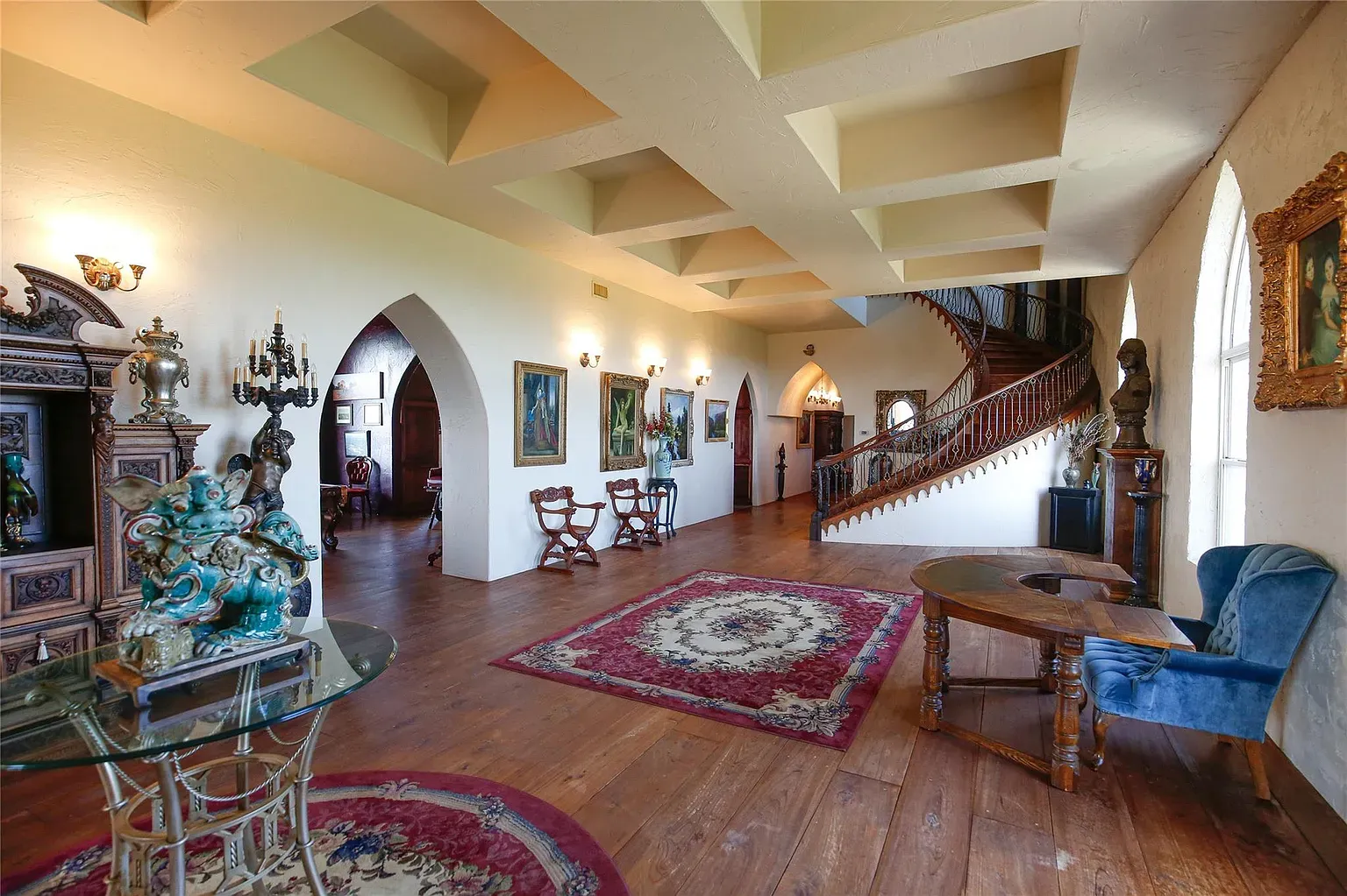 Entryway is all arches and that red-gold rug. Warm wood underfoot.