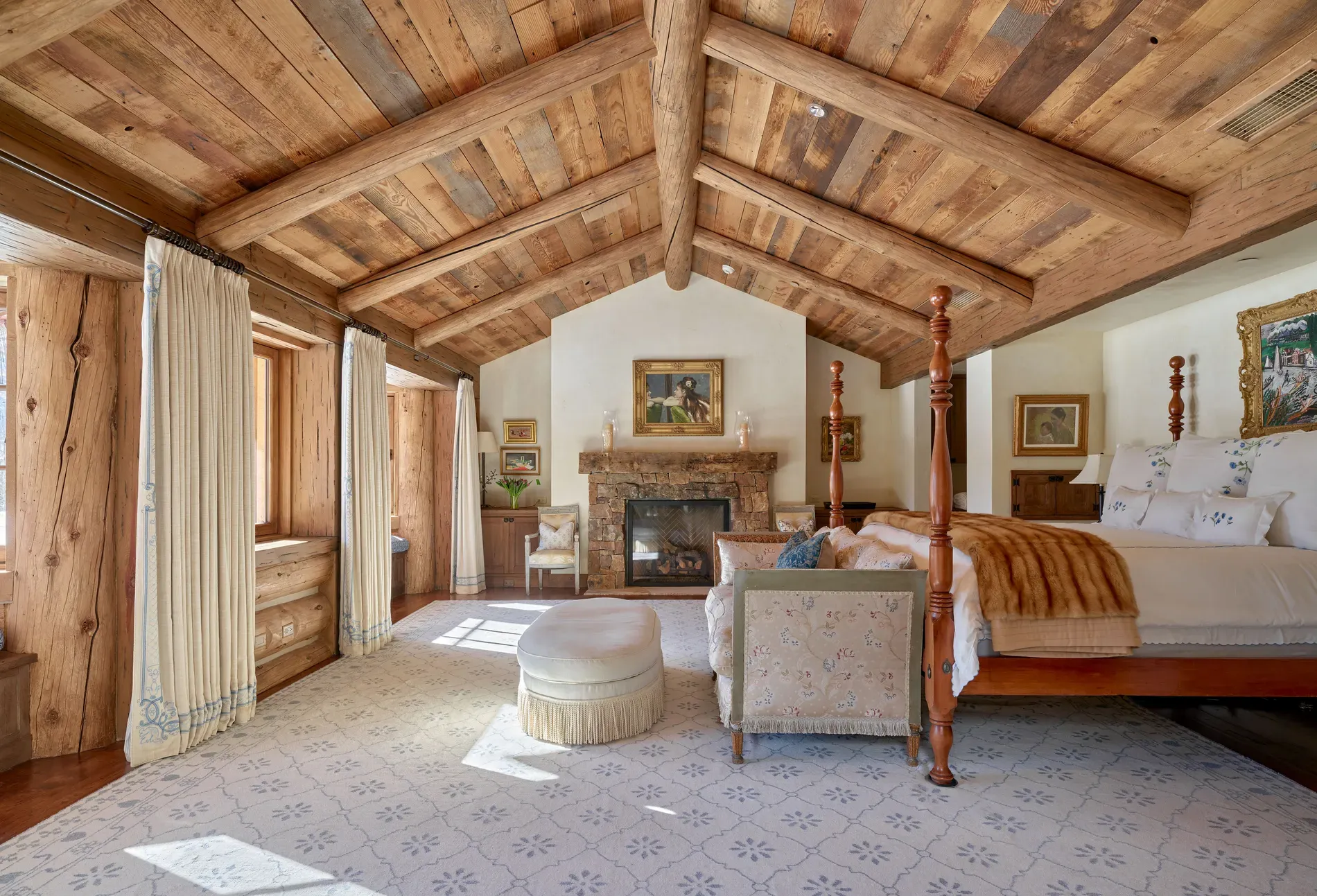 Bedroom again — vaulted beams, soft cream walls. Elegant without losing cabin soul.