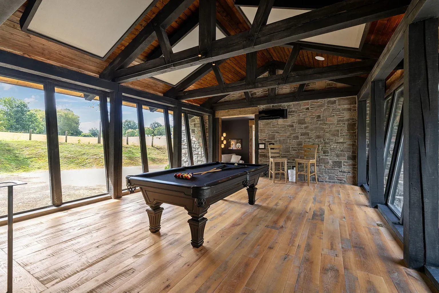 Vaulted ceiling, black pool table, and those huge windows begging for a rainy-day game.