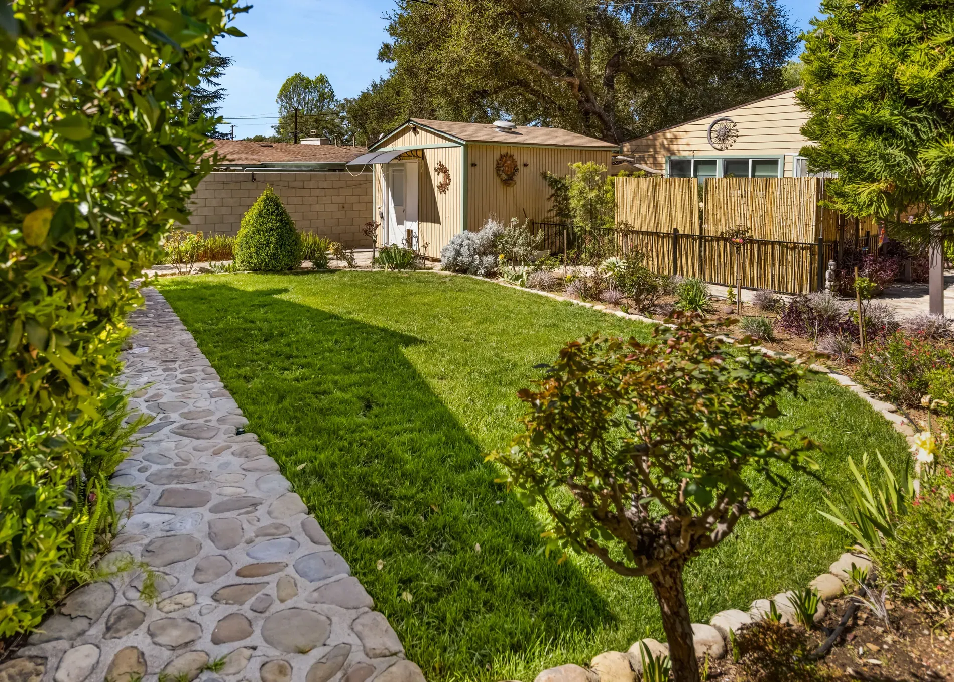 Emerald lawn with a winding cobblestone path. Garden beds look dialed in.