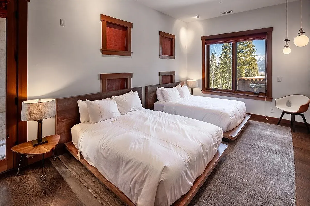 Two low wooden beds, soft whites, super quiet guest room vibes.