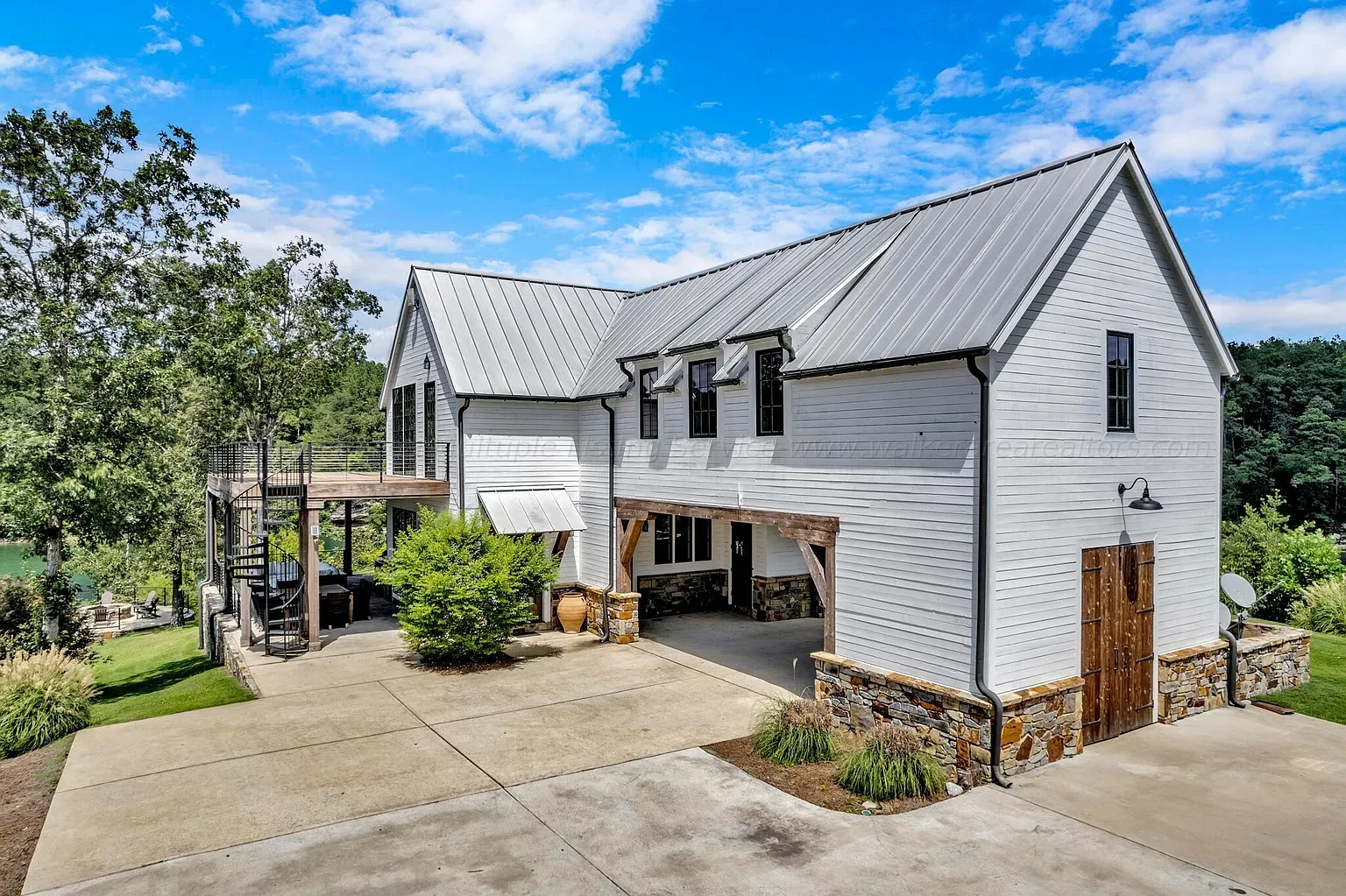 White siding with stone base and metal roof. Windows are doing the most.