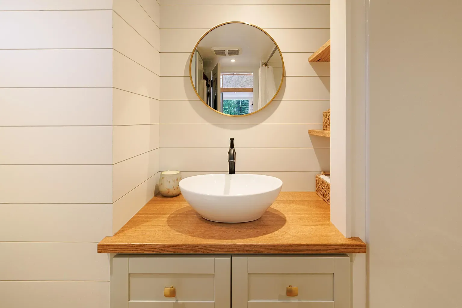 Round gold mirror steals it. Vessel sink looks a tiny sculpture.