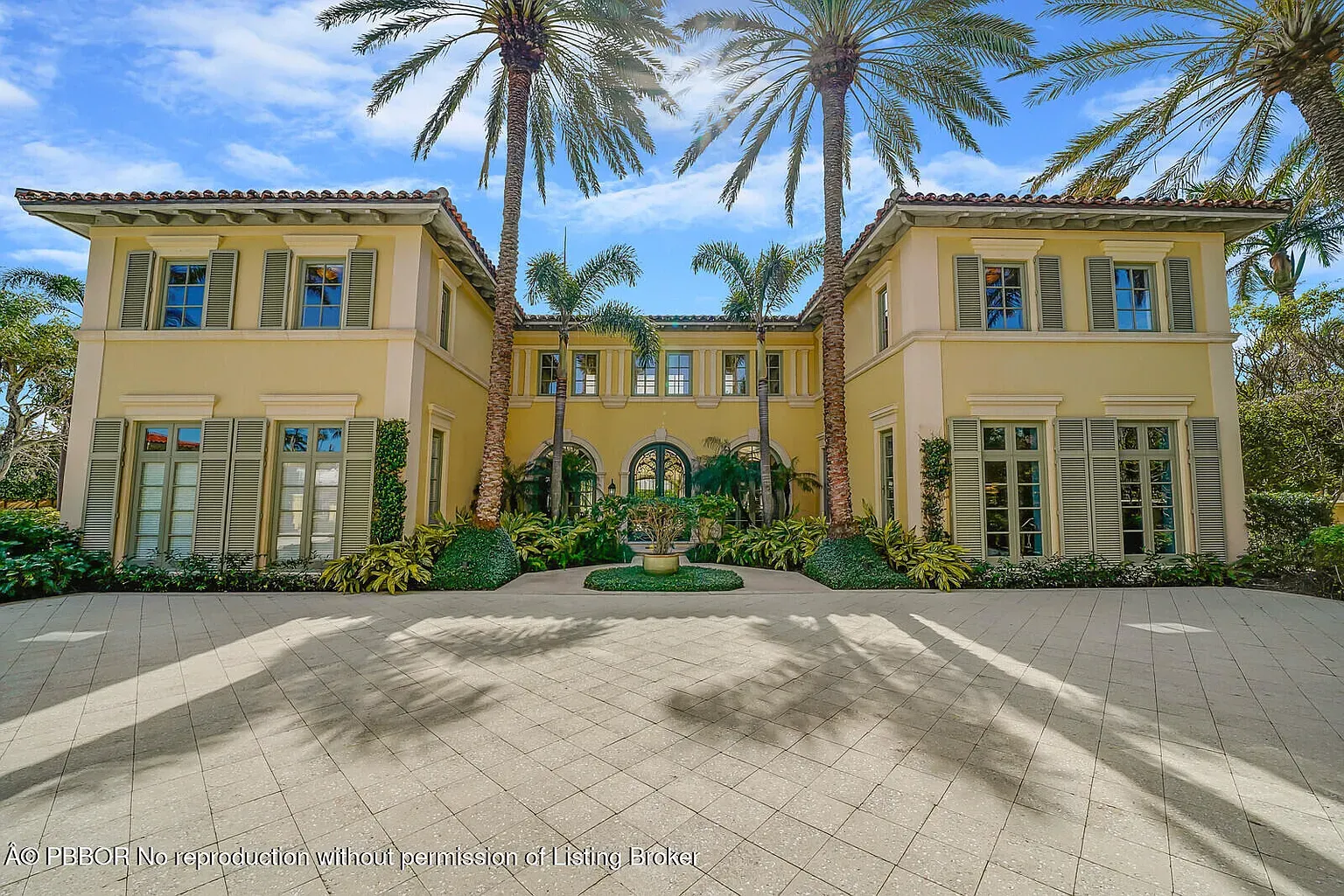 Here's the front — buttery stucco, super symmetrical, palms doing the drama.