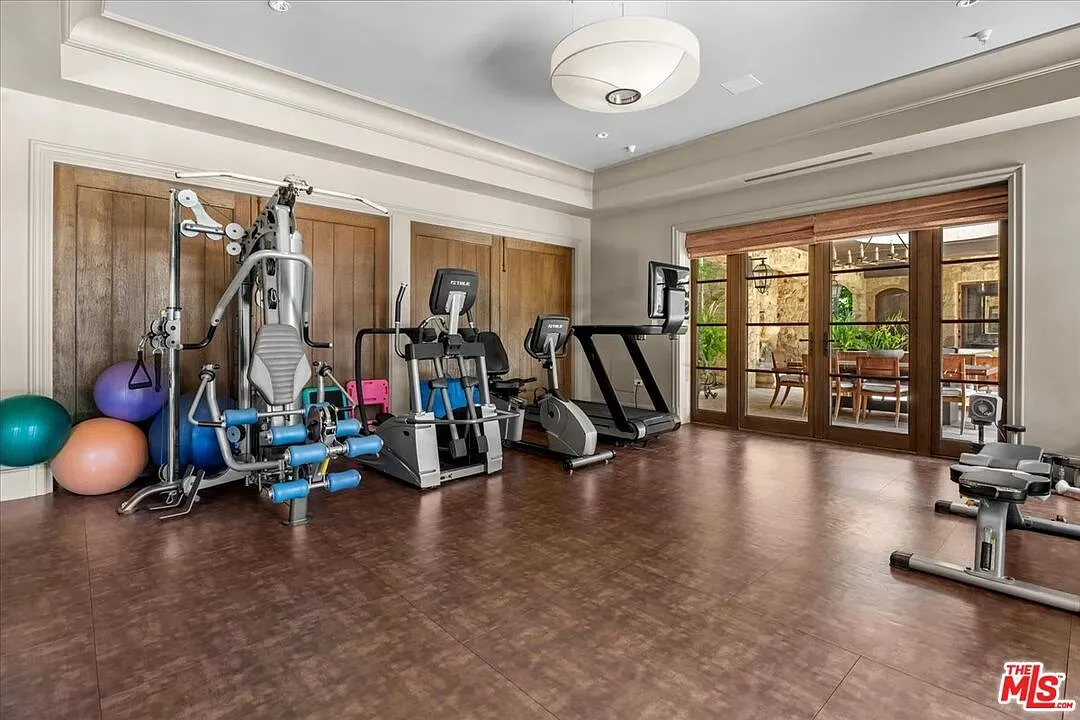 Home gym with dark floors, gray walls, and an actual chandelier.
