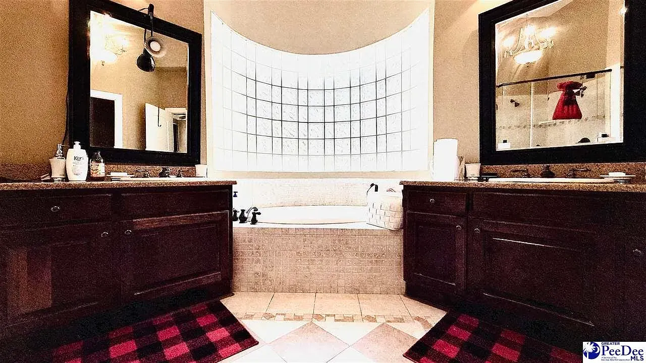Double vanity with rich wood and granite. Mirrors make it feel huge.