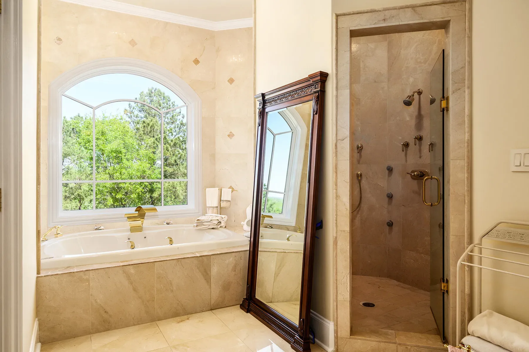 Spa moment. marble everywhere, soaking tub under an arched window to trees.