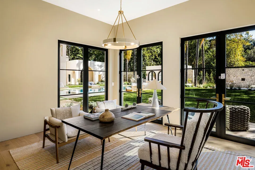 Home office with giant black-framed windows. Garden and pool staring back.