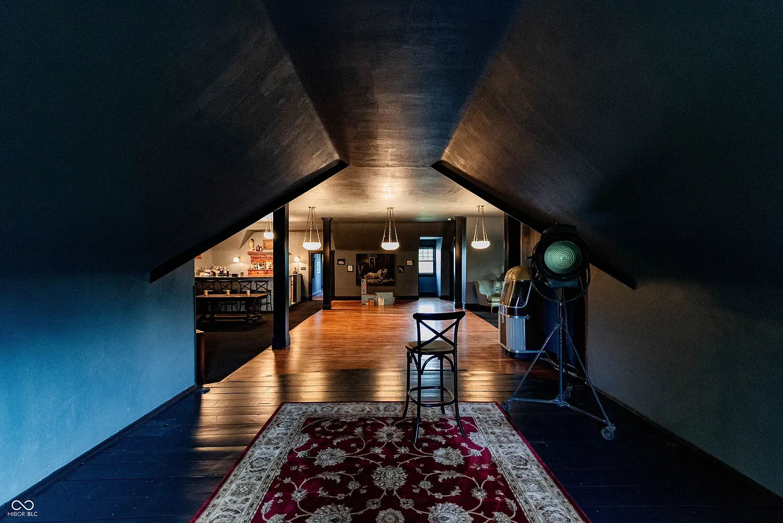 Attic lounge with sloped ceilings and dark paint. Cozy movie-night headquarters.