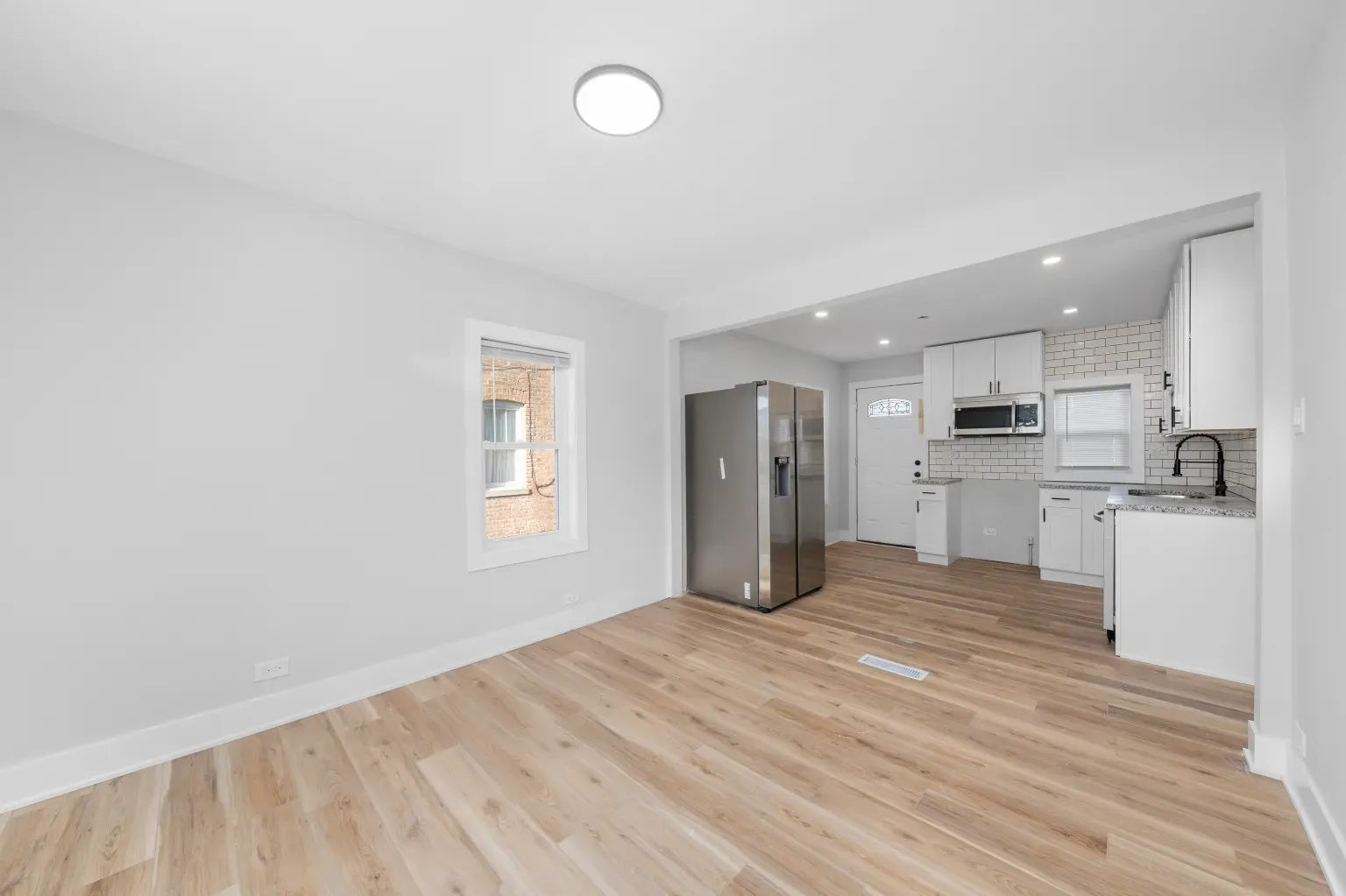 Open kitchen/dining—soft white and pale floors. Bright, easy vibe. Plenty breathing room.