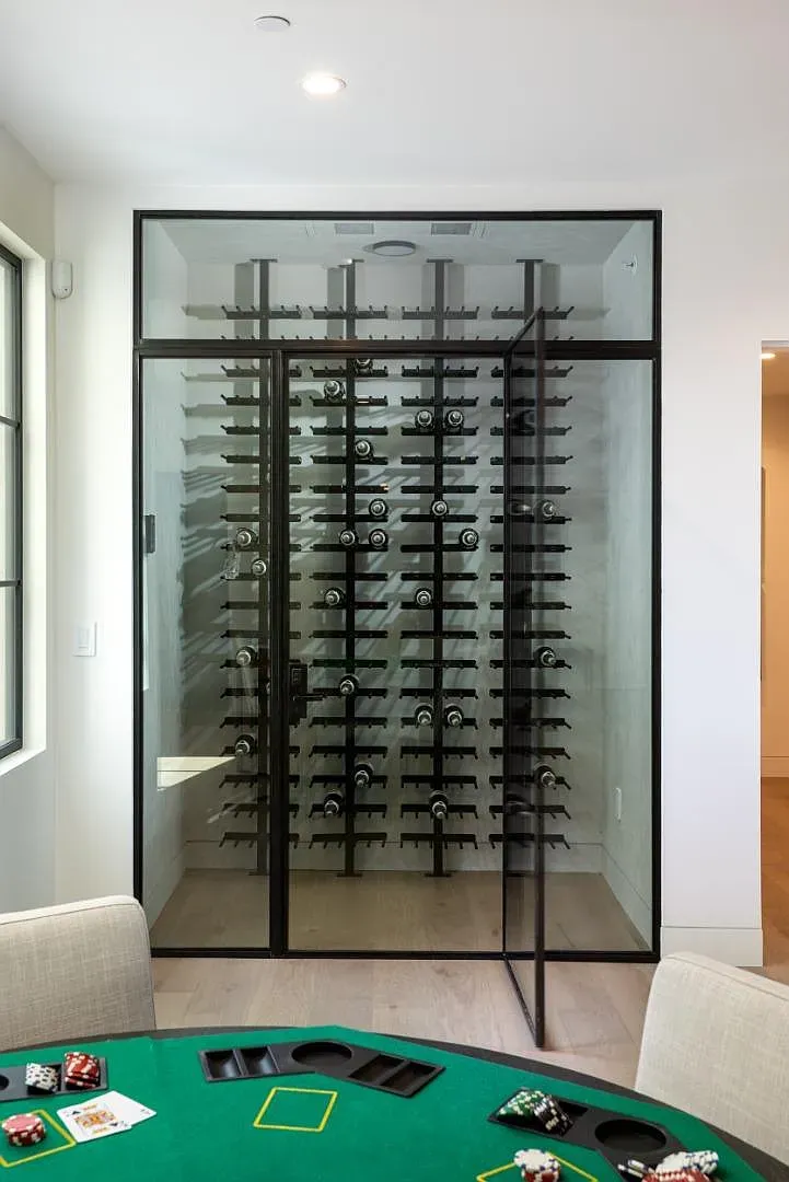 Glass-enclosed wine wall with black trim. Labels lined up trophies.