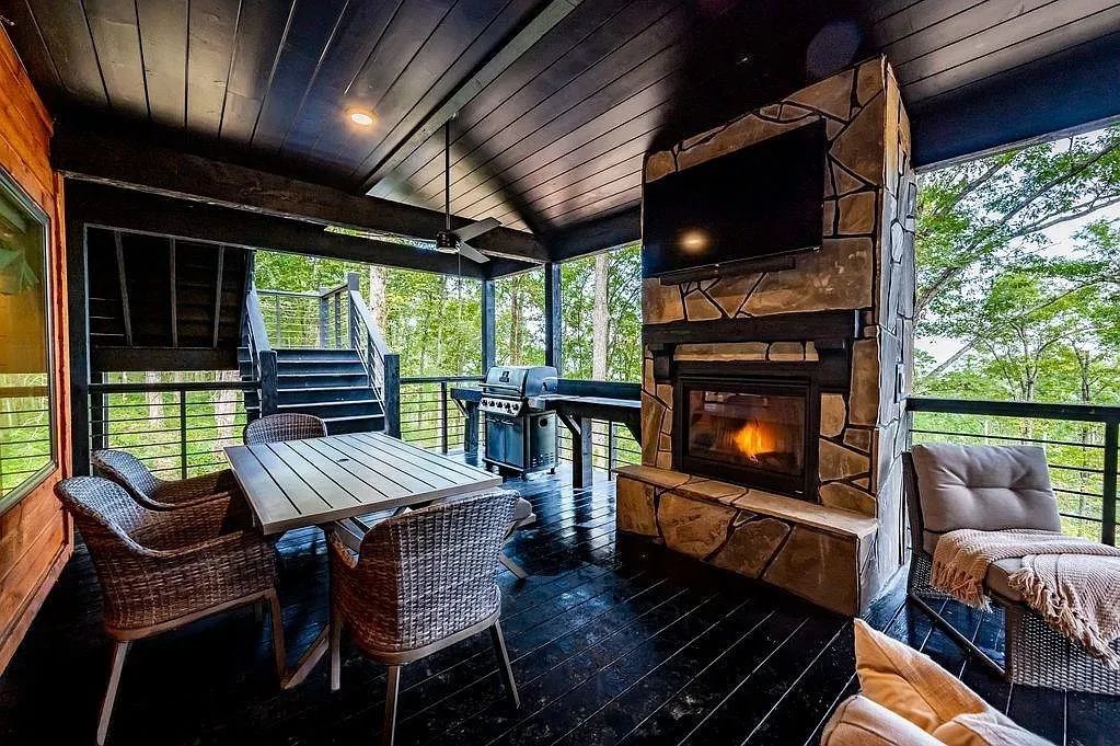 Outdoor dining zone. Big natural table, woven chairs, black ceiling keeps it modern.