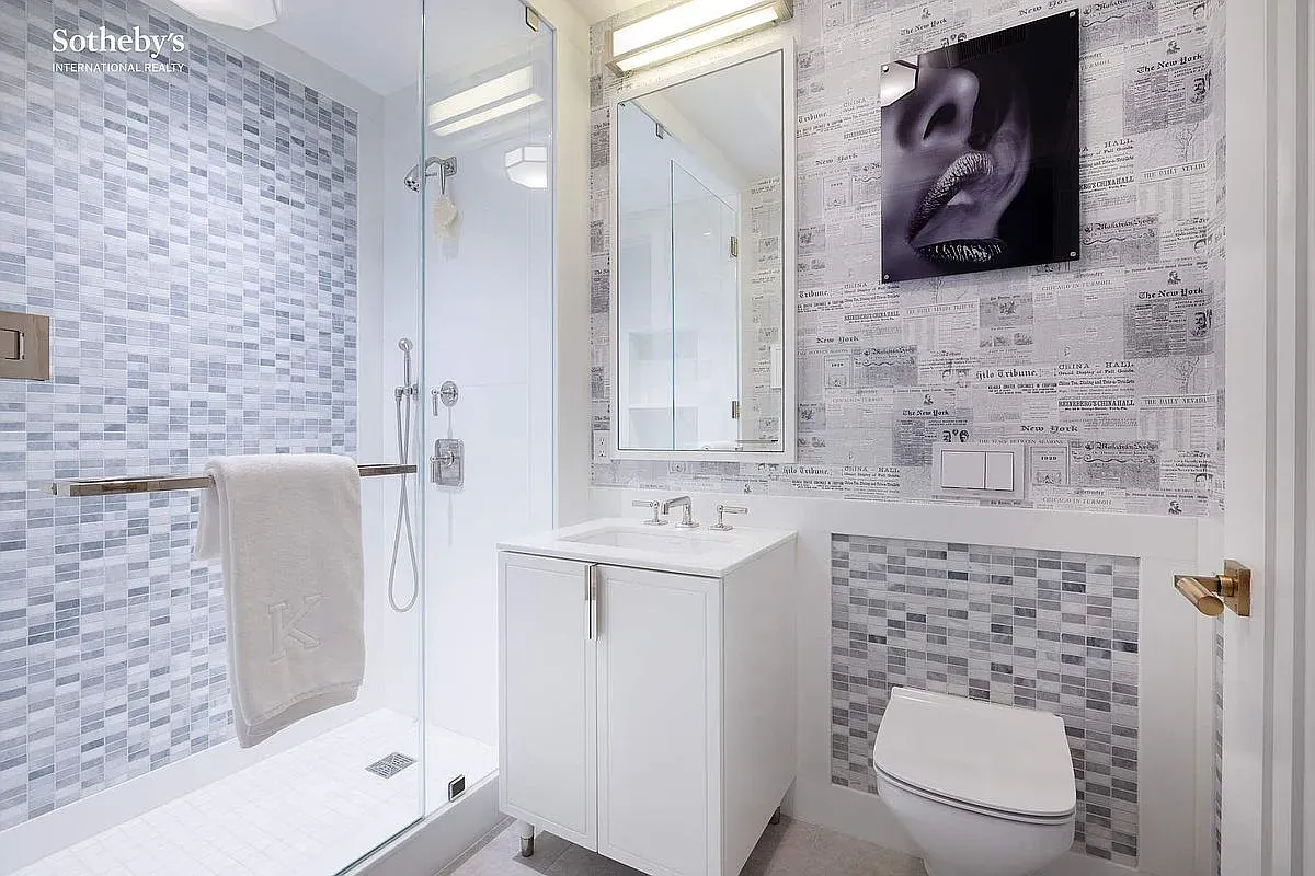 Clean white-gray bath, big glass shower. This angle makes it feel endless.
