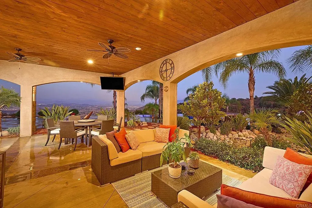 Covered patio with wood beams and stone floors. Lights make it glow at dusk.