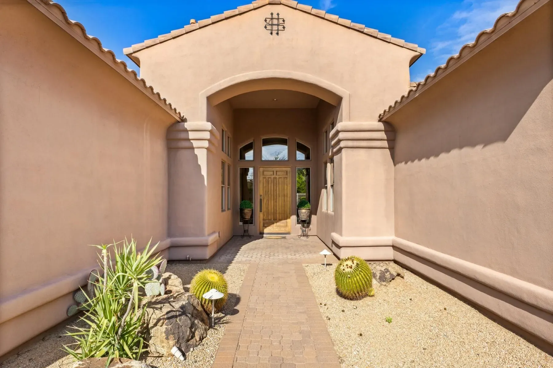 Arched stucco entry with stone accents. Southwest vibes turned up just right.