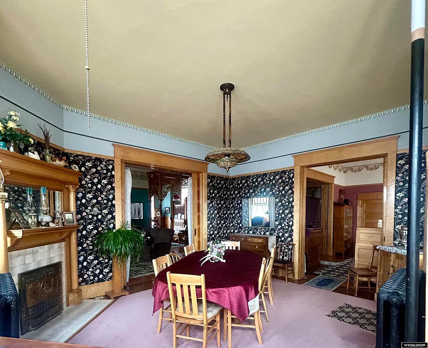 Burgundy tablecloth in the dining room. Simple chairs, warm light, holiday-ready.
