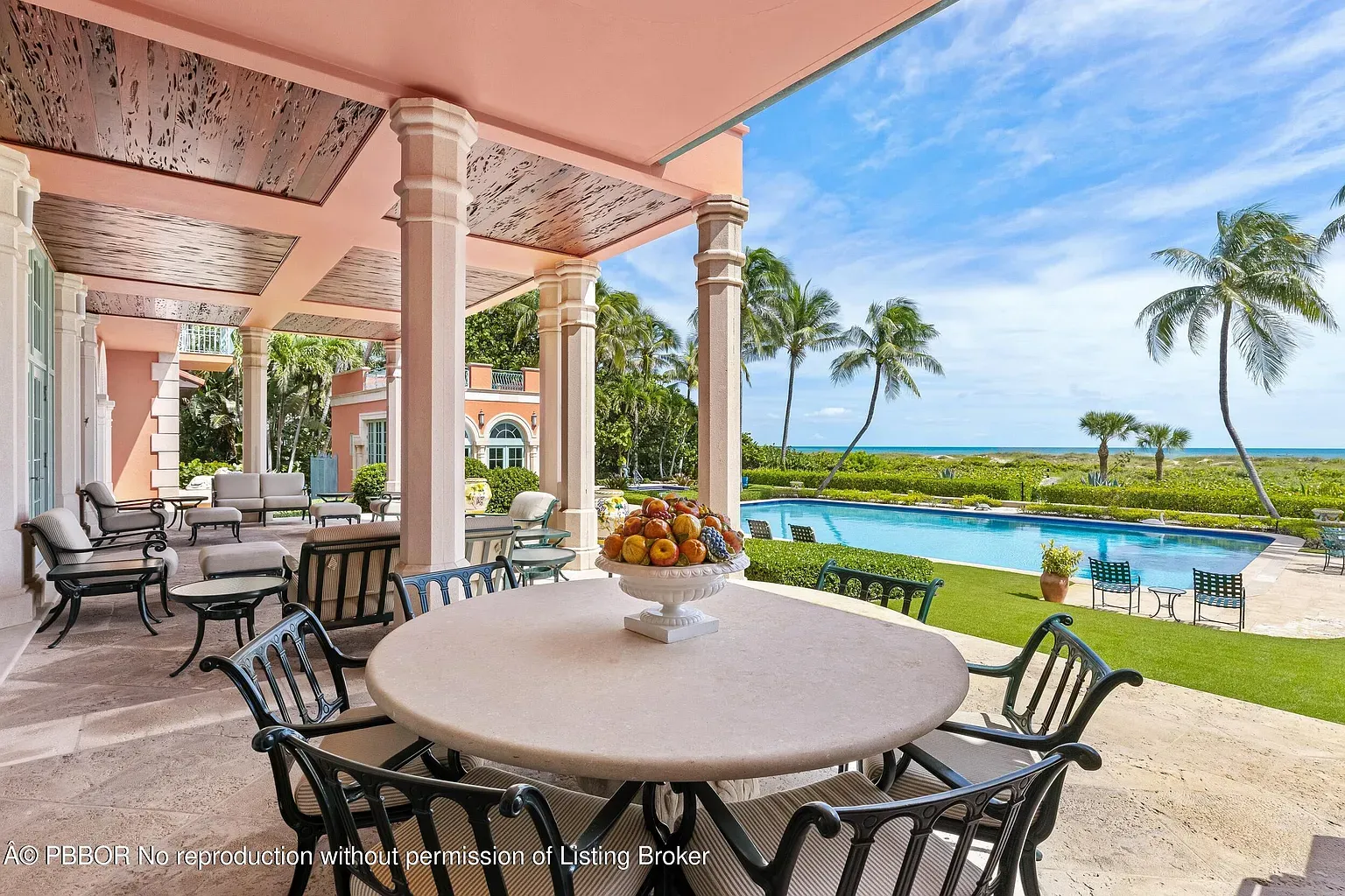 Round stone table set for ocean-view dinners. Pool right there too.
