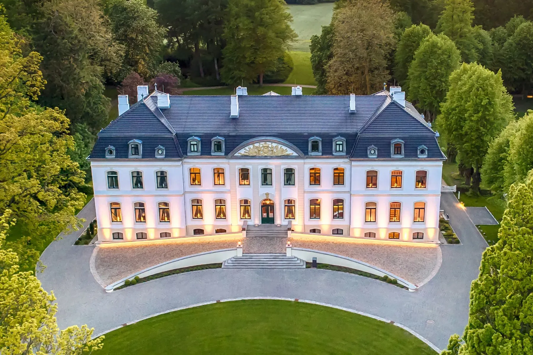 Symmetrical white manor with the slate roof and chimneys flexing.
