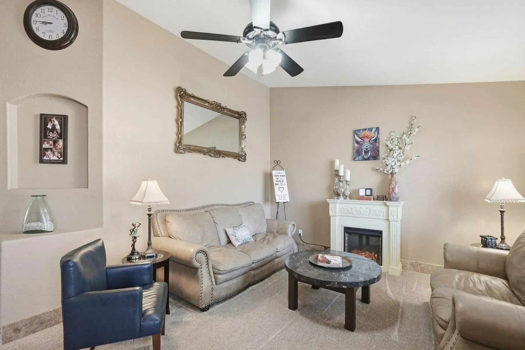Beige living room with ornate mirror over the fireplace. Pretty traditional.