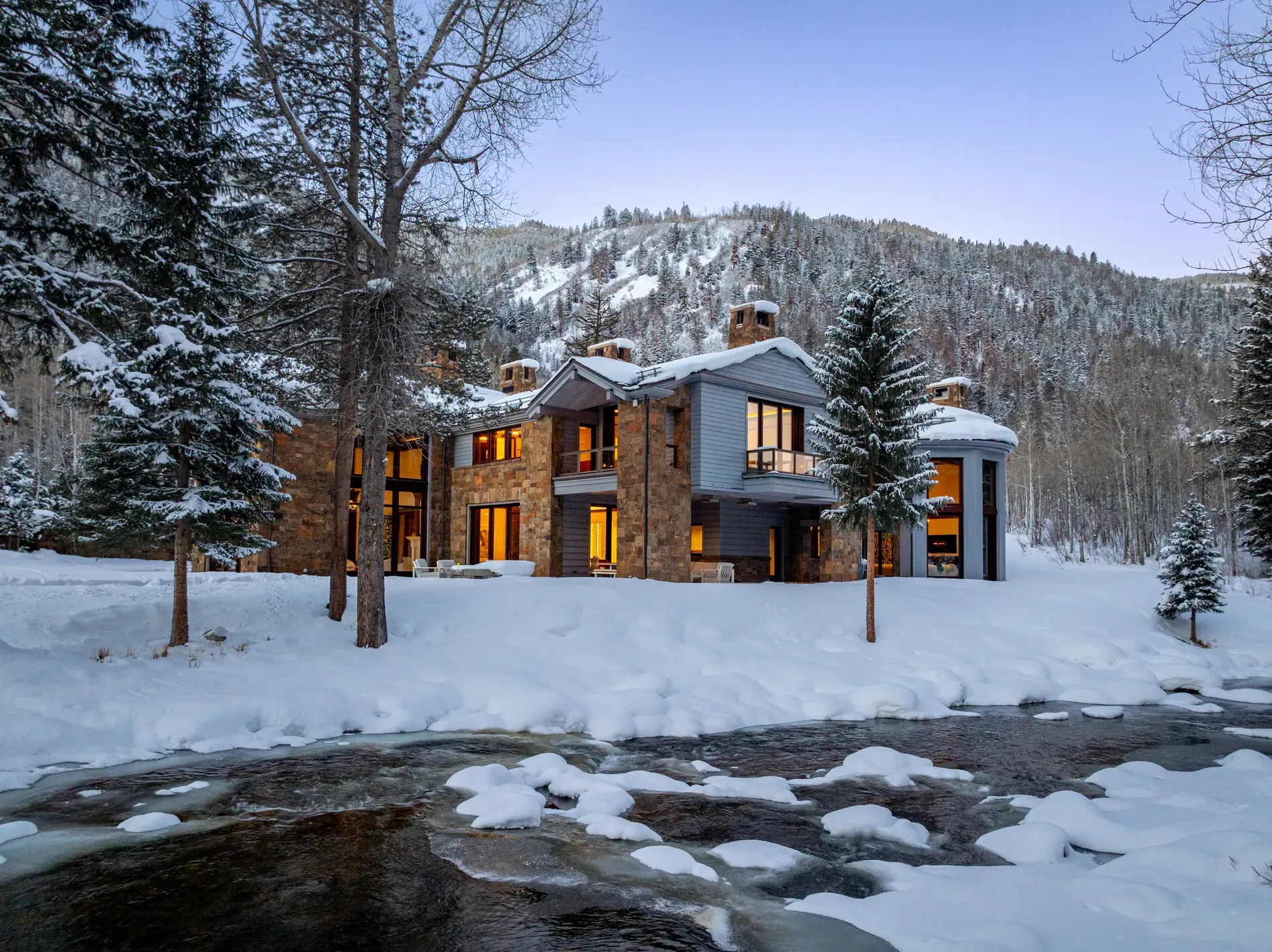 Here's the mountain retreat—stone and wood, huge dark windows reflecting snow.