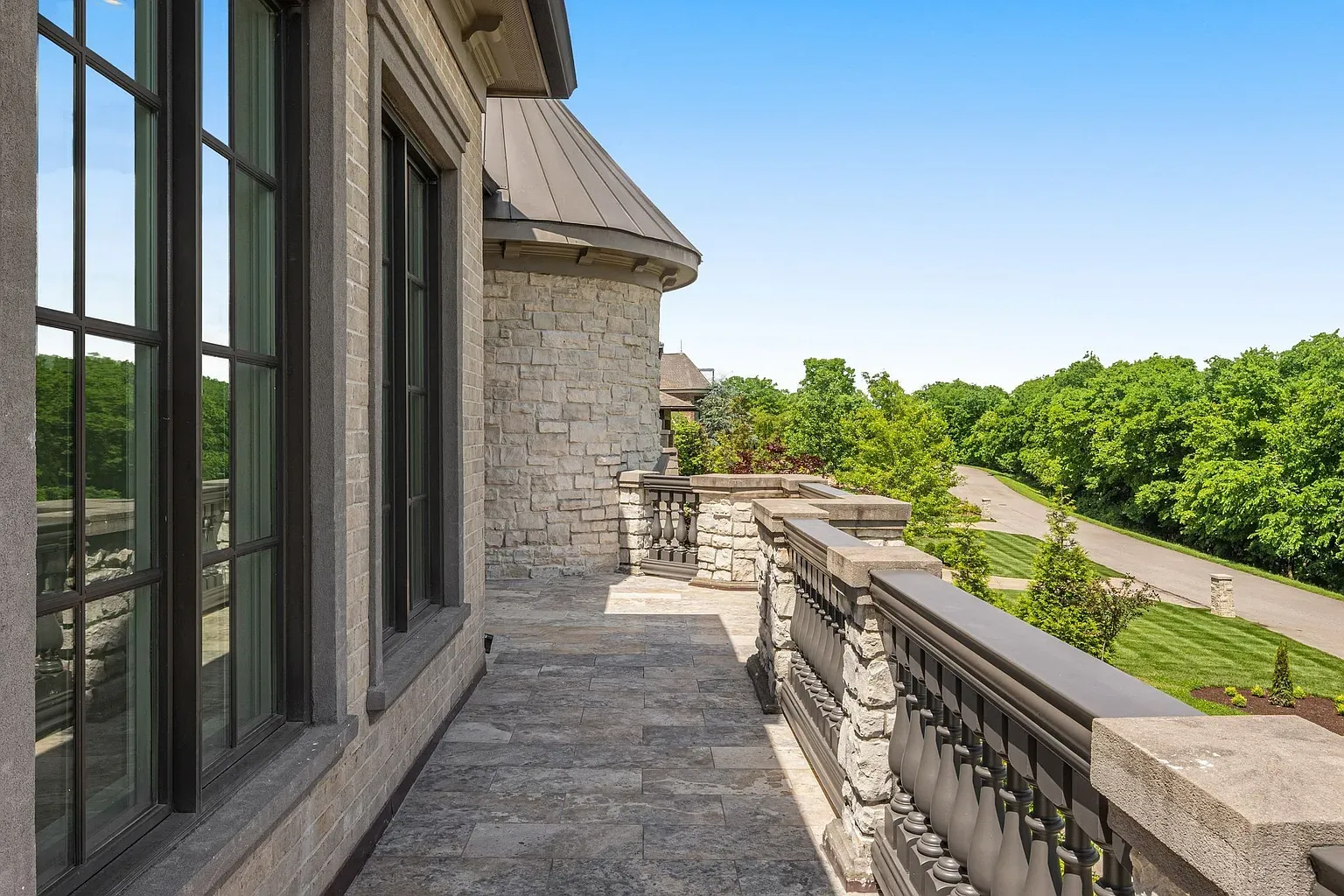 Terrace in soft gray stone, simple railings, big views. Bring the evening drinks.
