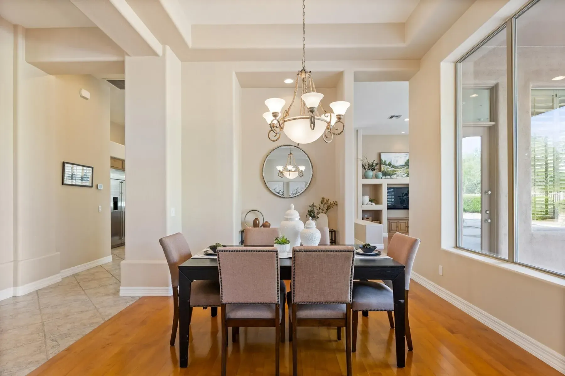 Simple dining setup. dark table, taupe chairs, five-light chandelier doing its thing.