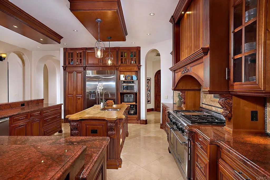Carved mahogany cabinets and glass fronts, plus a massive granite island. Fancy but warm.