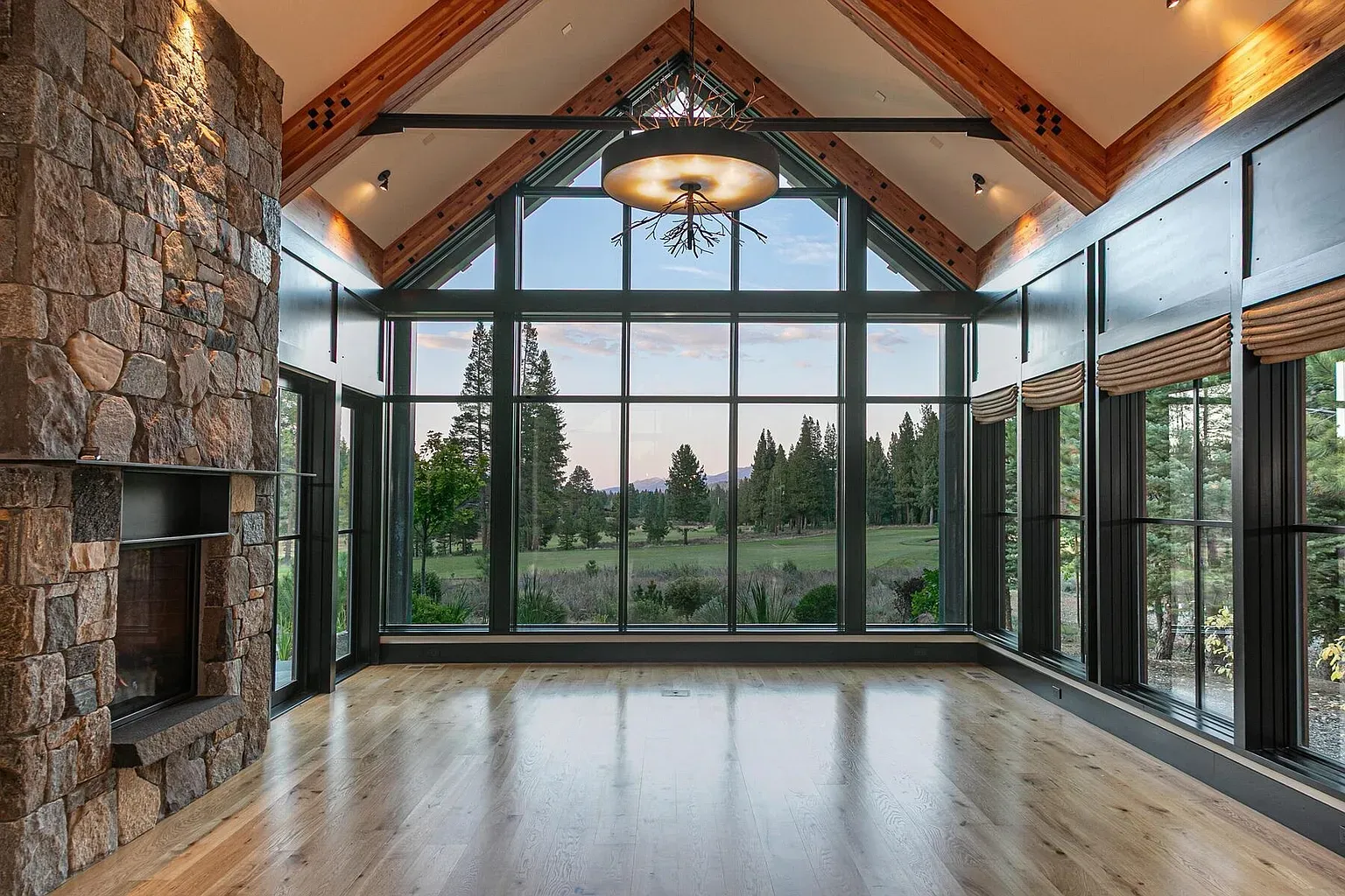 Great room goals. floor-to-ceiling windows, chunky stone fireplace, mountains framed art.