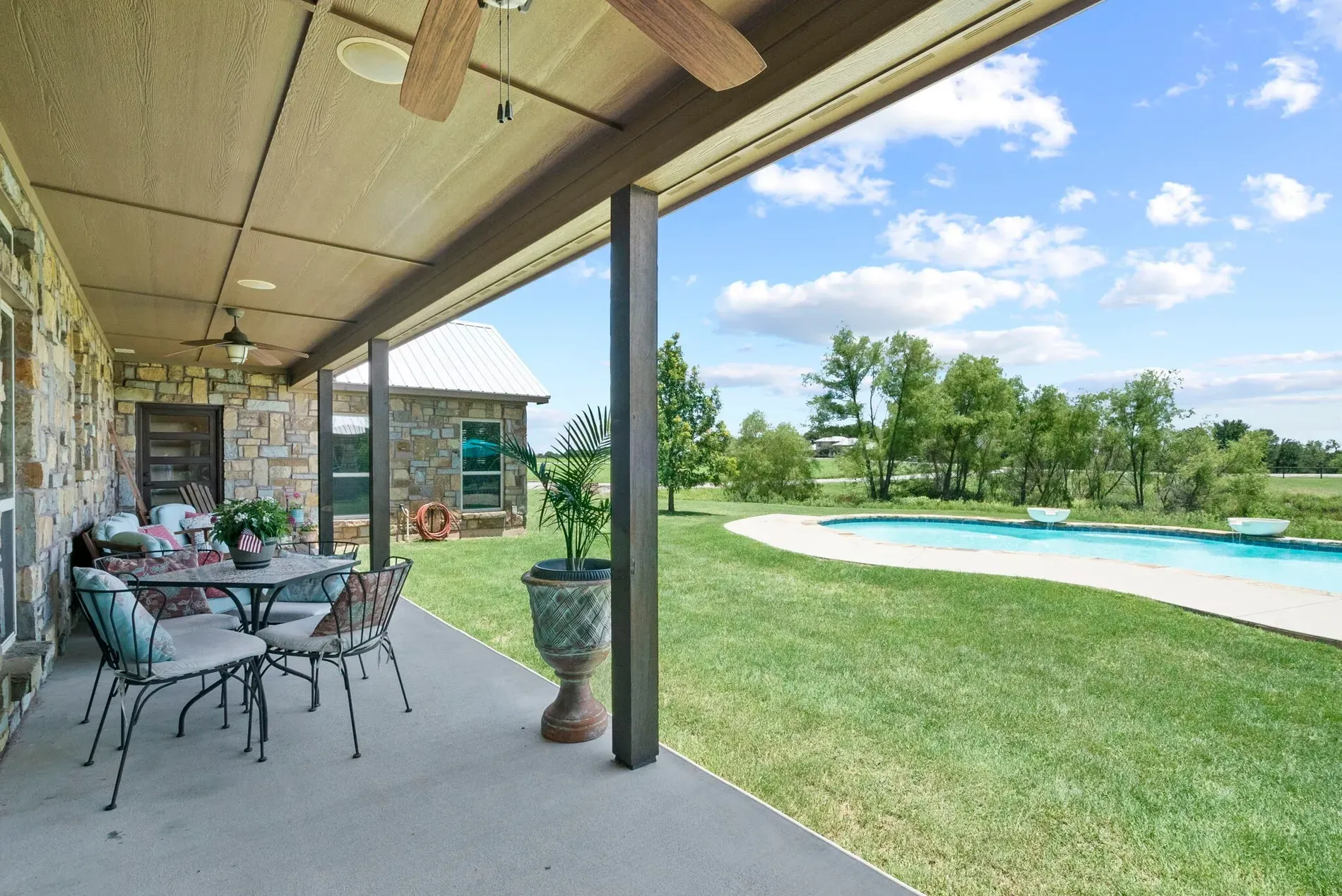 Covered stone patio tucked into the trees. I’m hearing birds and a sizzle.