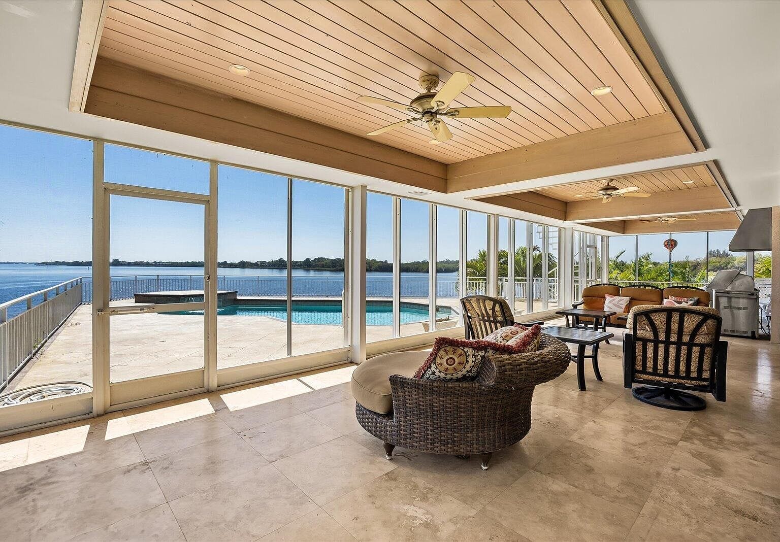 Screened-in lanai with patio furniture overlooking the pool