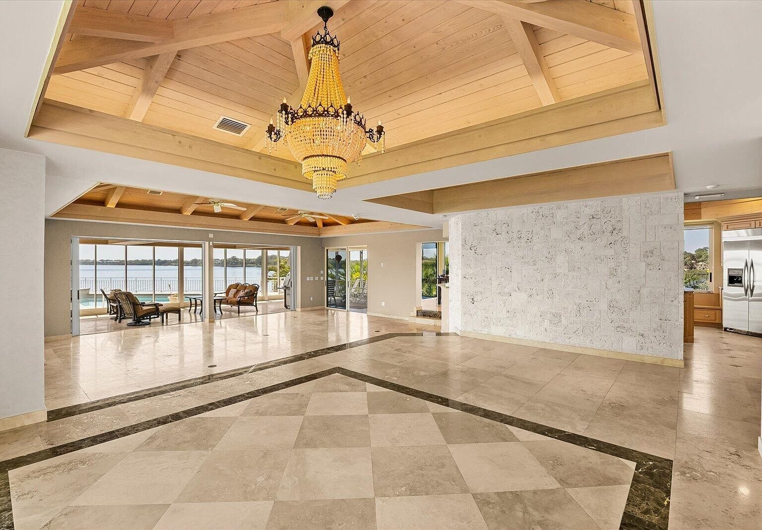 Wide open foyer with a massive gold chandelier and polished tile floors