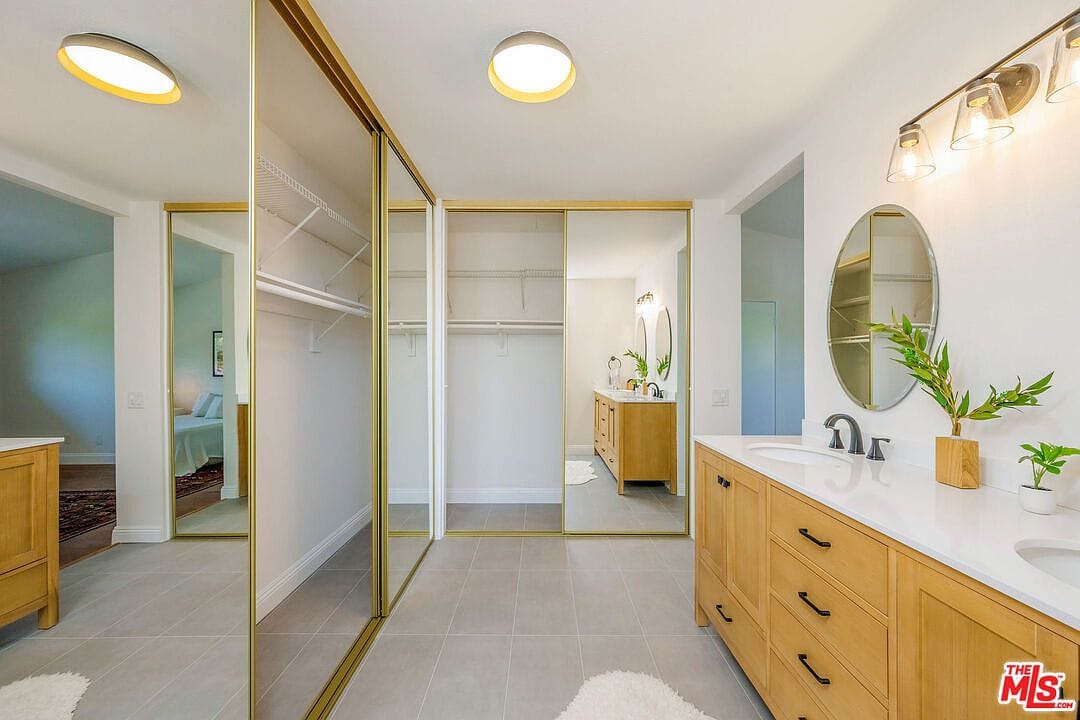 Remodeled primary bathroom with light wood vanity and gold mirrors