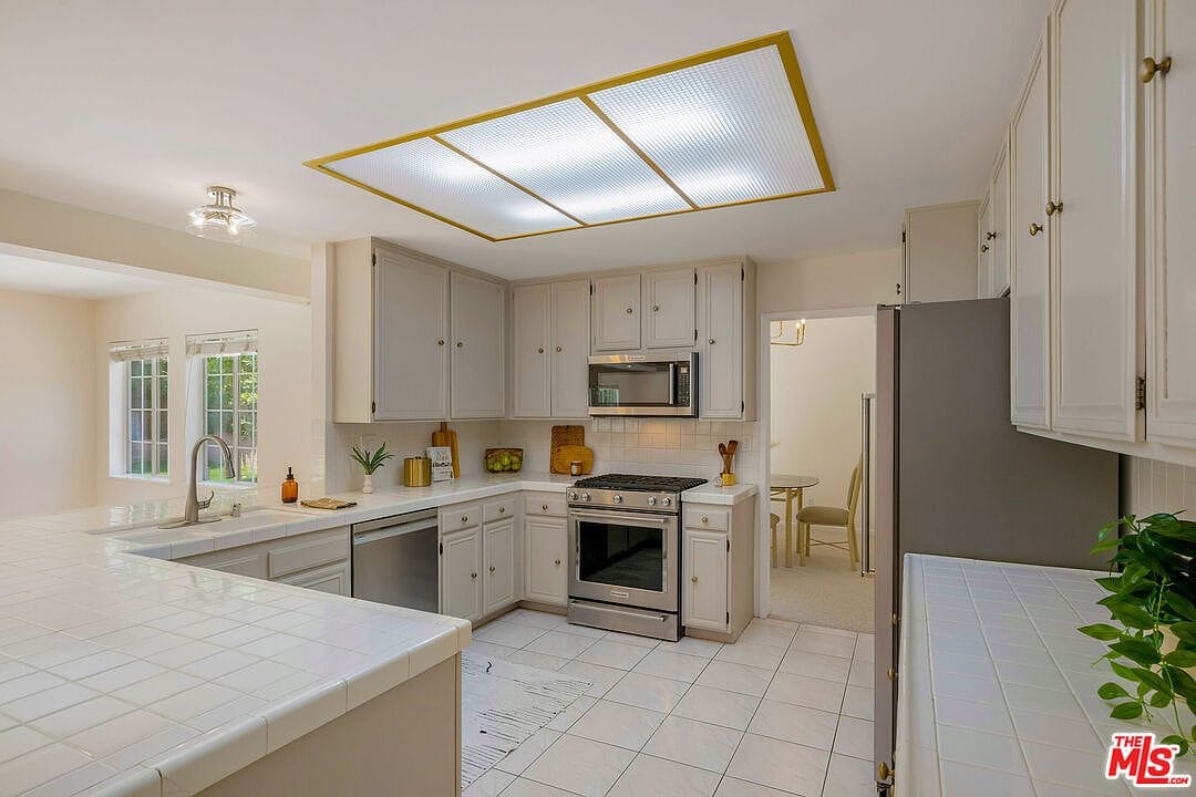 U-shaped kitchen with beige cabinets and stainless steel appliances