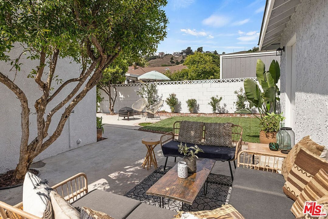 Outdoor seating area with a sofa, coffee table, and white block wall
