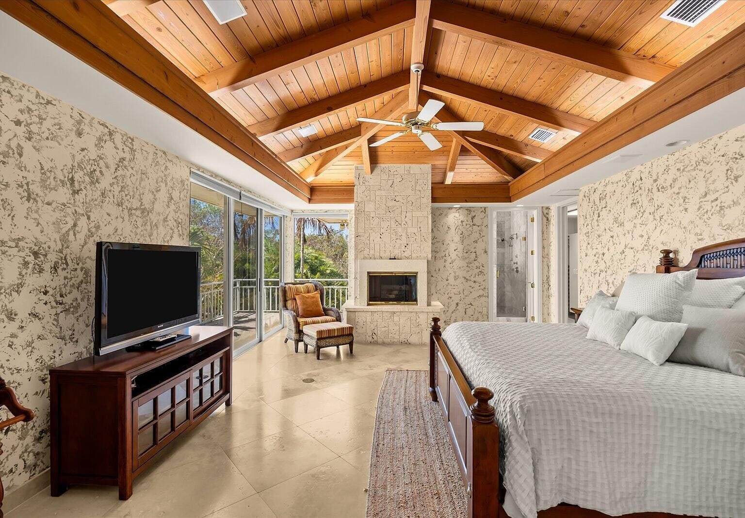 Bedroom with a tall stone fireplace and wood ceiling